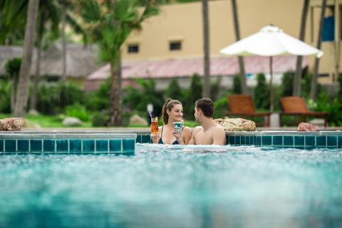 a man and woman sitting in a swimming pool at Muong Thanh Holiday Muine Hotel in Mui Ne
