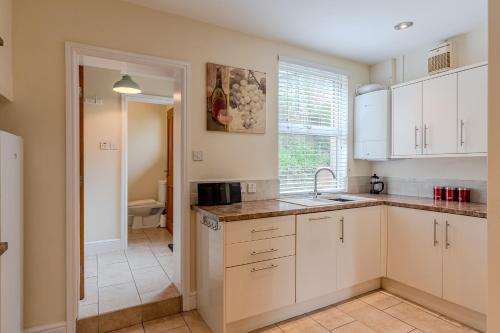 a kitchen with white cabinets and a sink at Esk Valley House in Sleights