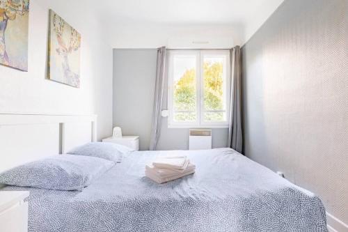 - une chambre blanche avec un lit et une serviette dans l'établissement Appartement moderne Boulogne sur Mer proche de la plage et Nausicaa, à Boulogne-sur-Mer
