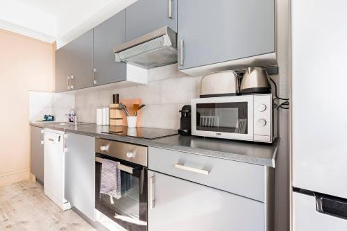 une cuisine avec des armoires blanches et un micro-ondes dans l'établissement Appartement moderne Boulogne sur Mer proche de la plage et Nausicaa, à Boulogne-sur-Mer