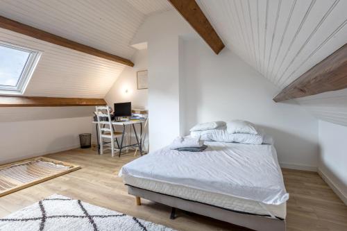 - une chambre mansardée avec un lit et un bureau dans l'établissement Maison 12pers 3kms de la plage, à Plozévet