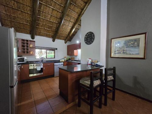 a kitchen with a counter and chairs and a clock at Glen Afric Country Lodge in Hartbeespoort