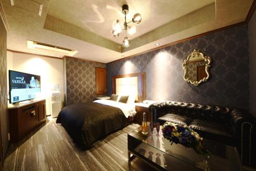 a bedroom with a bed and a couch and a television at Hotel Vanilla Komaki (Adult Only) in Komaki