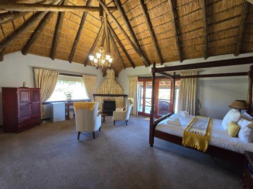 a bedroom with a bed and chairs in a room at Glen Afric Country Lodge in Hartbeespoort