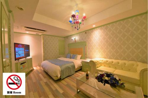 a bedroom with a bed and a couch and a tv at Hotel Vanilla Komaki (Adult Only) in Komaki