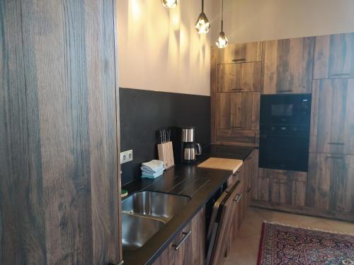uma cozinha com um lavatório de aço inoxidável e armários de madeira em La Grande Ferme Maison de Maître em Crépon