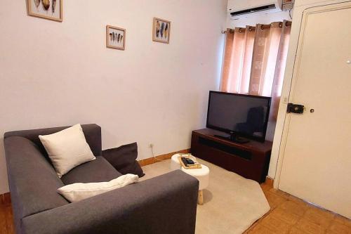 uma sala de estar com um sofá e uma televisão em Pet friendly T1 sossegado c/ pátio espaçoso em Luanda