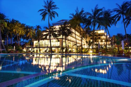 a hotel with a swimming pool in front of a building at Muong Thanh Holiday Muine Hotel in Mui Ne