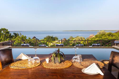 a table with chairs and wine glasses on a balcony at The Cabanas Lamu in Lamu