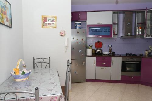 a kitchen with purple cabinets and a table and a refrigerator at Toni Apartment Berat in Berat