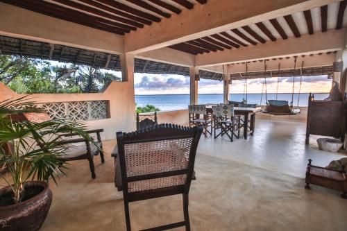 a porch with chairs and tables and the ocean at The Cabanas Lamu in Lamu