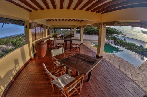 an outdoor deck with tables and chairs and a pool at The Cabanas Lamu in Lamu