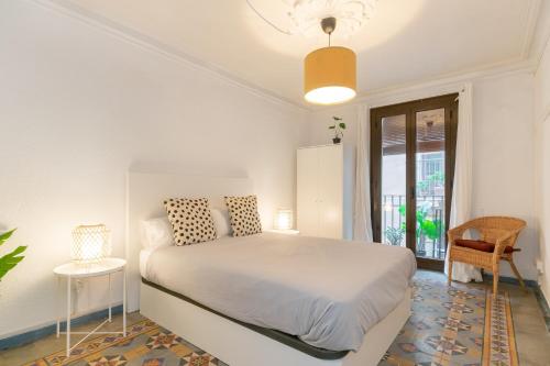 a white bedroom with a bed and a window at VEGUER in Barcelona