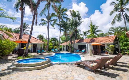 a resort with a swimming pool and palm trees at Garden By The Sea in Sosúa