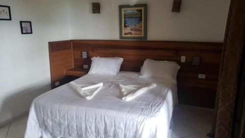 a bed with white sheets and pillows on it at Pousada Cantinho D'Abrantes in Ilhabela