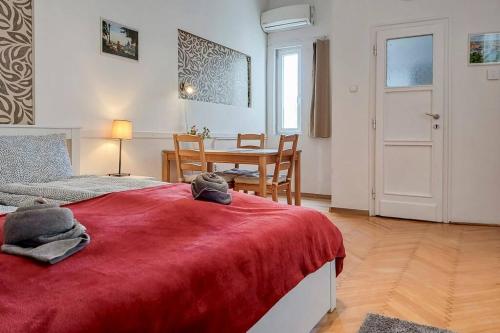 Schlafzimmer mit einem roten Bett, einem Tisch und einem Stuhl in der Unterkunft Astoria Apartment in Budapest