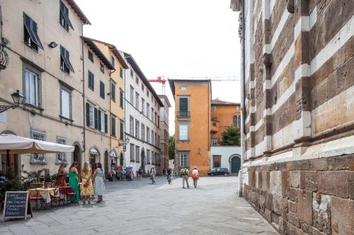 a group of people walking down a street with buildings at Appartamento San Giovanni in Lucca