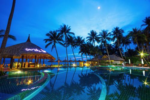 a swimming pool at night with palm trees at Muong Thanh Holiday Muine Hotel in Mui Ne