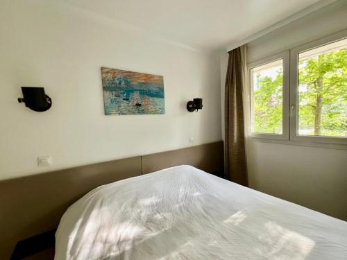 une chambre avec un lit blanc et une fenêtre dans l'établissement Cosy 1BR Apt in Modern Residence Paris La Défense, à Courbevoie