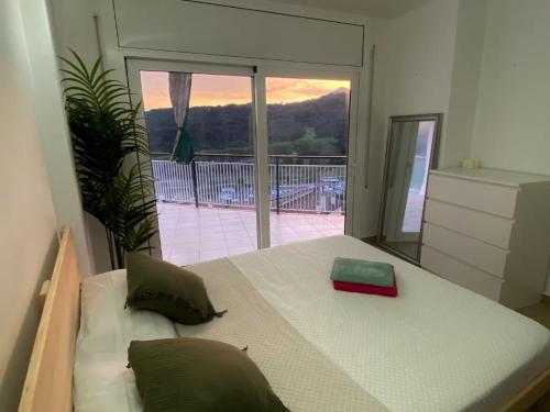 Schlafzimmer mit einem Bett und einem großen Fenster in der Unterkunft Piso con piscina in Arenys de Munt