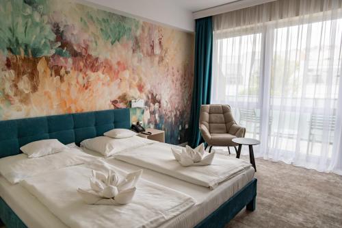 a bedroom with two beds and a chair and a painting at Hotel Atlantis Medical, Wellness & Conference in Hajdúszoboszló