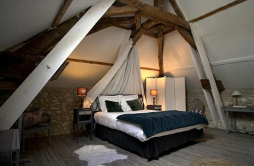 ein Schlafzimmer mit einem Himmelbett in einem Zimmer mit Balken in der Unterkunft La Vigenna in Dangé