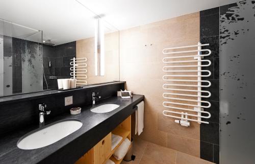 a bathroom with two sinks and a mirror at Waldhotel Arosa in Arosa