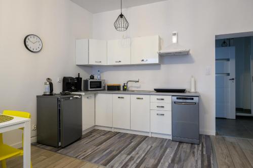 una cocina con armarios blancos y un reloj en la pared en Apartamenty Czary Mary, en Bardo