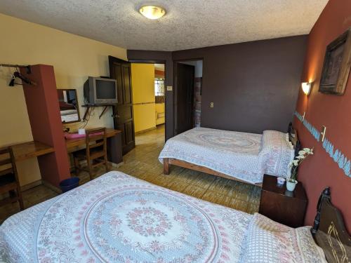 a hotel room with two beds and a desk at Hotel del Parque in Uruapan del Progreso