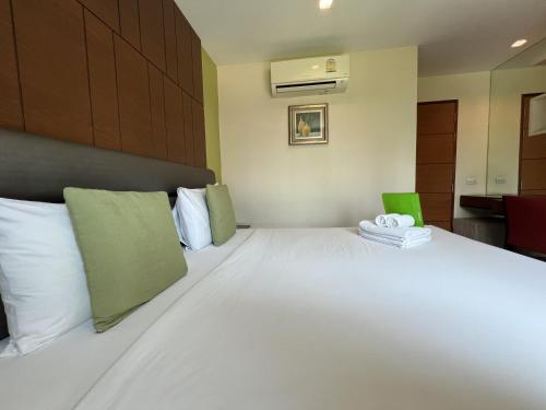 a bedroom with a large white bed with green accents at Silom Forest Exclusive Residence in Bangkok