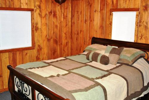 een bed in een slaapkamer met houten wanden en ramen bij ATV Getaway in Gladwin