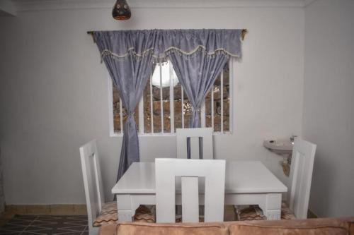 a table and chairs in a room with a window at Mella Homes Limuru in Kiambu