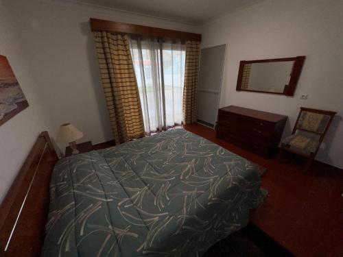 - une chambre avec un lit, une commode et un miroir dans l'établissement Alojamento Vila Flor, à Praia da Vitória