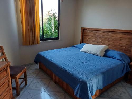 una camera da letto con un letto con una coperta blu e una finestra di Rústica Azul a Tlaxcala de Xicohténcatl