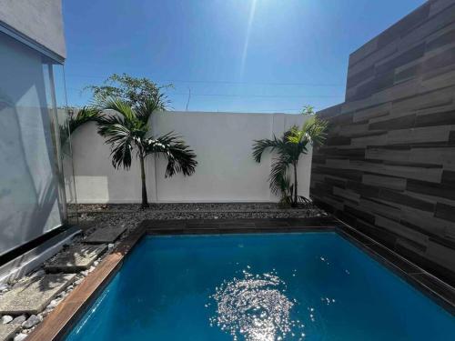 - une piscine bordée de palmiers à côté d'un bâtiment dans l'établissement Casa de lujo Altozano Residencial con Piscina by AIRA, 