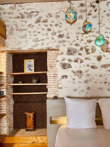 une chambre avec un lit et un mur en pierre dans l'établissement L'Atelier- Loft d'Artiste Aménagé, centre-ville, à Sète