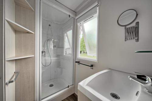 uma casa de banho branca com um chuveiro e um lavatório. em Chalet 2 em Salies-du-Salat