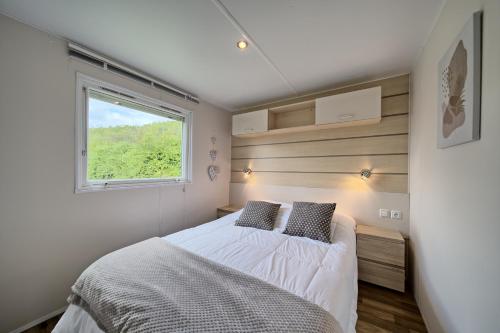um pequeno quarto com uma cama e uma janela em Chalet 2 em Salies-du-Salat