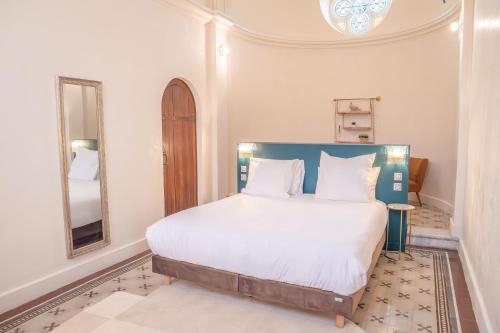 a bedroom with a bed with a blue headboard and a mirror at Château du Parc - Gîtes & spas à Pézenas in Pézenas