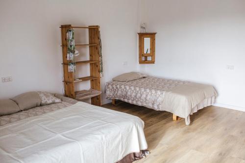 two beds in a room with white walls and wooden floors at Telšiai Inn in Telšiai