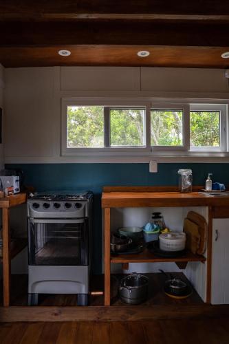 a kitchen with a stove and two windows at Nairandey in La Pedrera