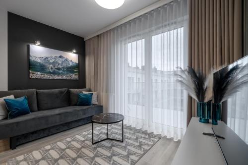 a living room with a couch and a large window at RentPlanet - Apartamenty Zakopiańskie in Zakopane