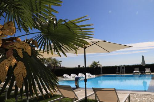 a swimming pool with chairs and an umbrella at Villa Nonna Cicci Boutique Hotel - SPA in Cisterna dʼAsti