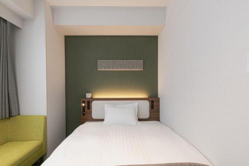 a small bedroom with a bed and a green wall at Shimanami PRIME HOTEL IMABARI in Imabari