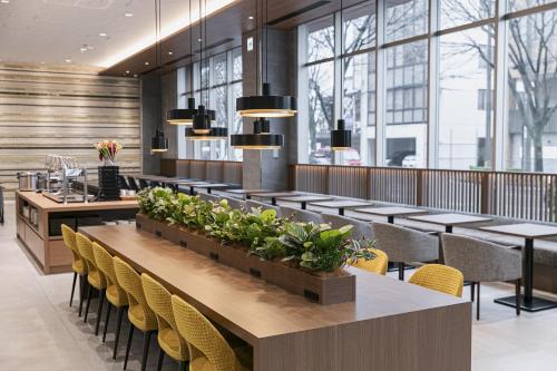 a dining room with tables and chairs and windows at Shimanami PRIME HOTEL IMABARI in Imabari