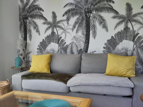 ein Wohnzimmer mit einem Sofa und Palmen an der Wand in der Unterkunft Le 101 - Plage du Dossen à Santec à 1.5 km in Santec
