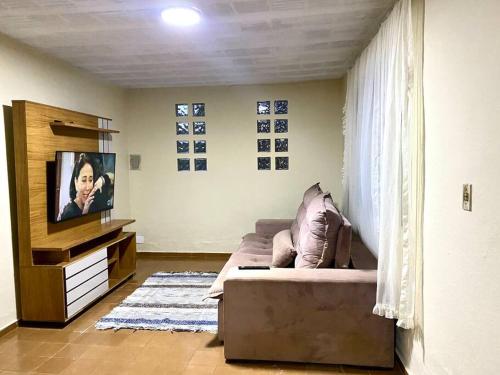 ein Wohnzimmer mit einem Sofa und einem Flachbild-TV in der Unterkunft Casa amarela in Juiz de Fora