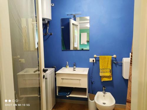 a blue bathroom with a sink and a toilet at Swimming and Sun in Gandosso