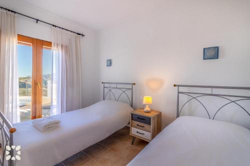 zwei Betten in einem Zimmer mit Fenster in der Unterkunft Villa Sunset Rock by Abahana Villas in Benitatxell