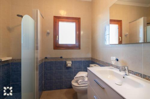 ein Badezimmer mit Toilette, Waschbecken und Spiegel in der Unterkunft Villa Sunset Rock by Abahana Villas in Benitatxell